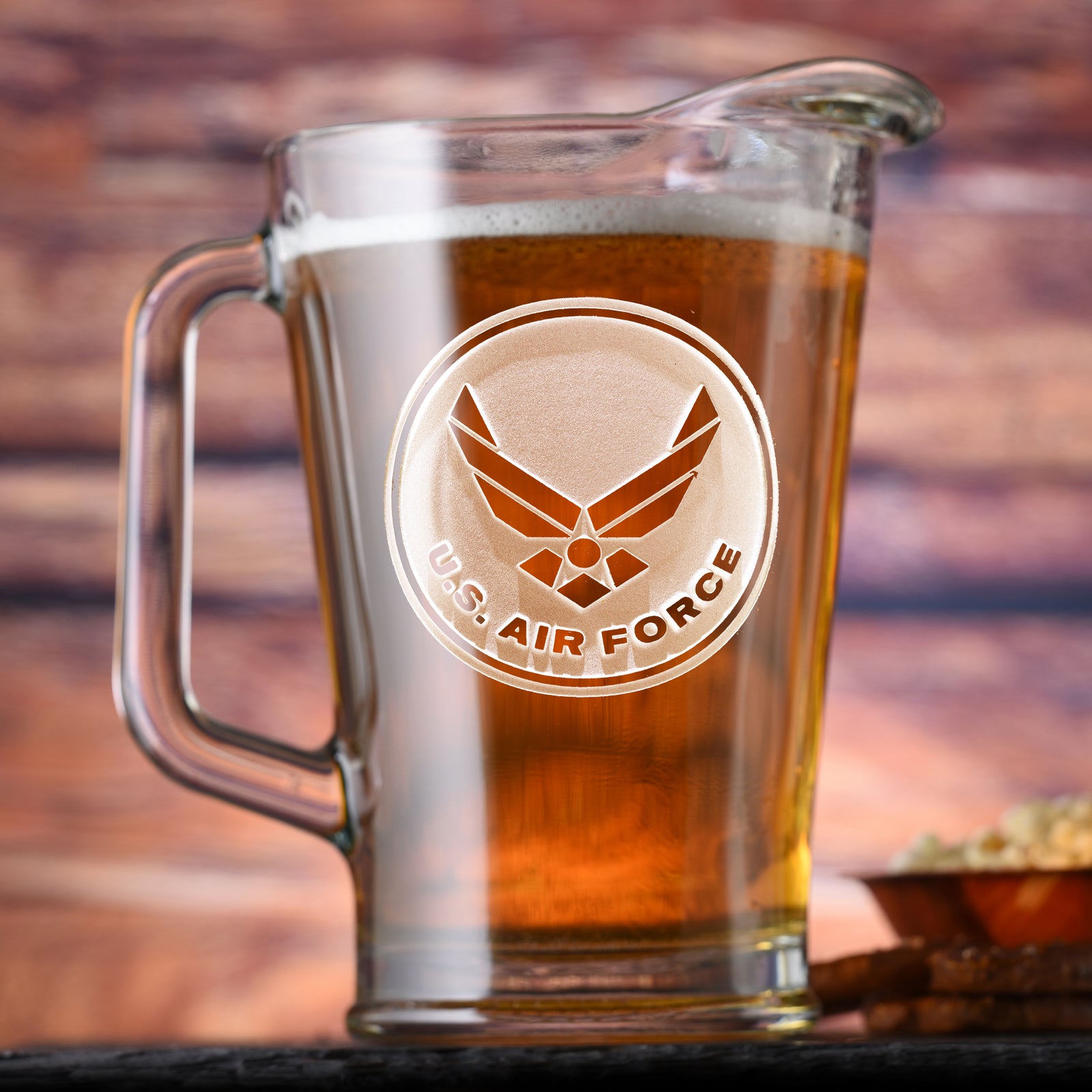 Glass beer pitcher filled with beer, deep-carved with the U.S. Air Force wings emblem in a circular badge.
