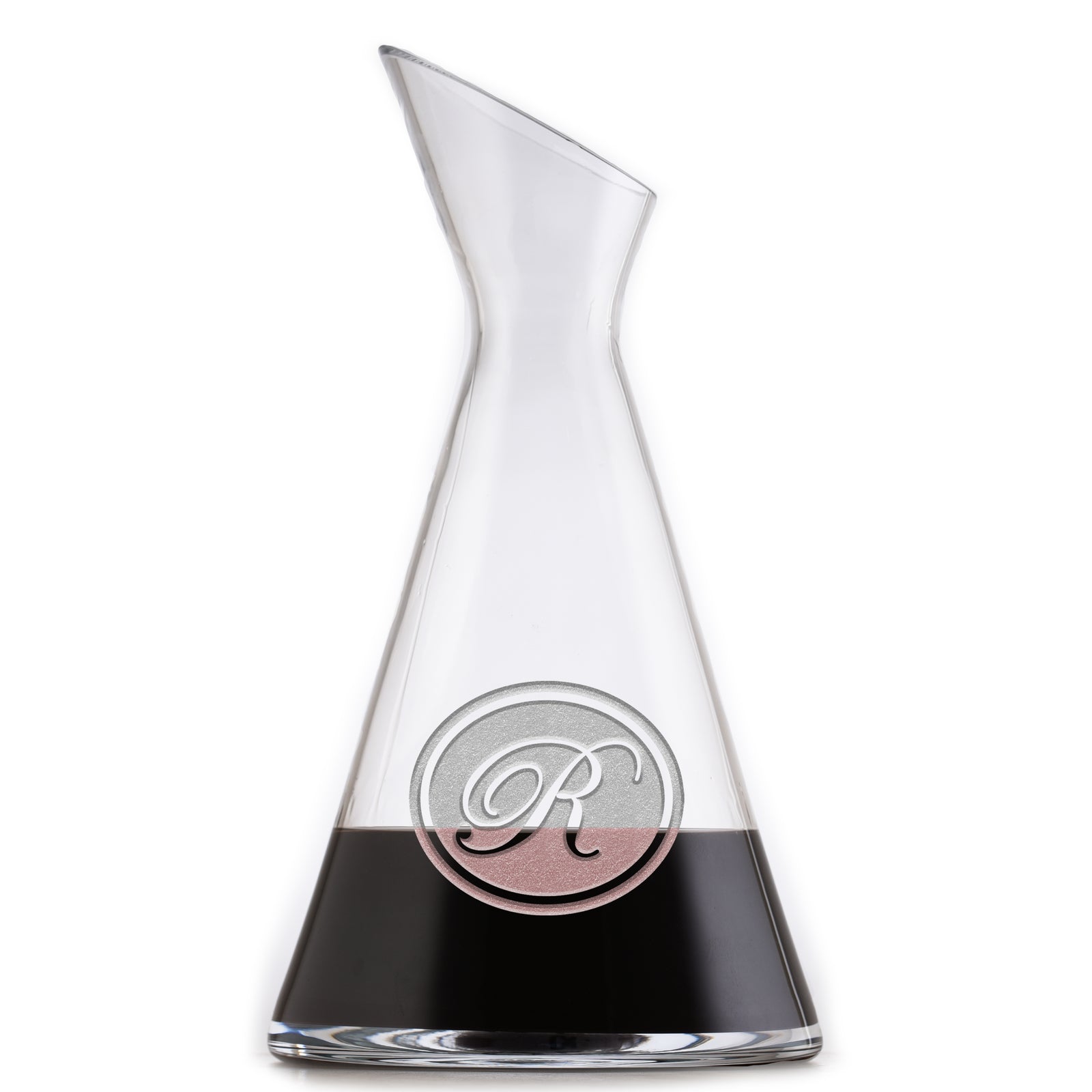 Slant wine carafe deep-carved with a script initial inside a thin circle, filled with a dark drink, on a white background.