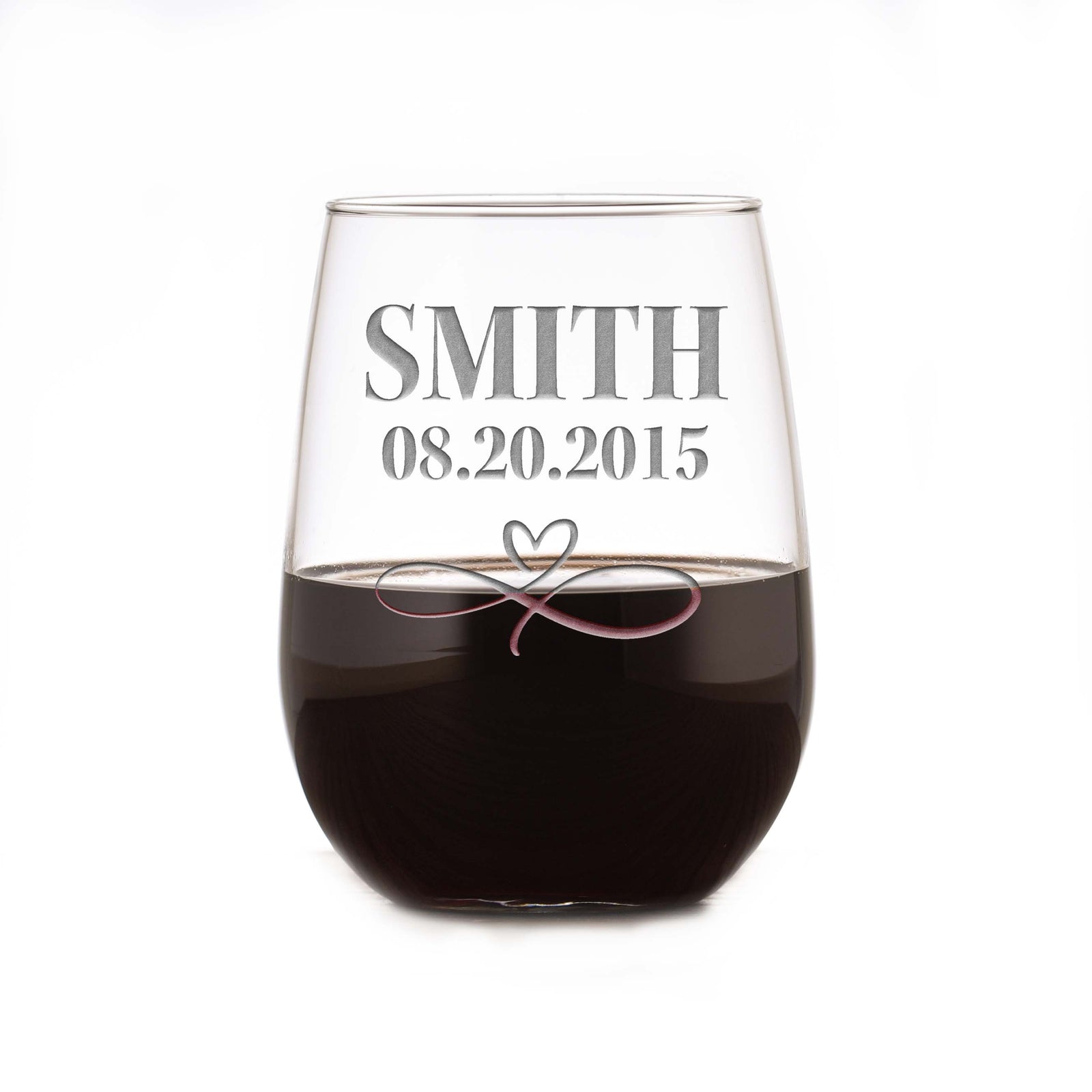 Stemless wine glass filled with dark wine, deep-etched with the name "Smith," the date "08.20.2015," and an infinity-heart design, on a white background.