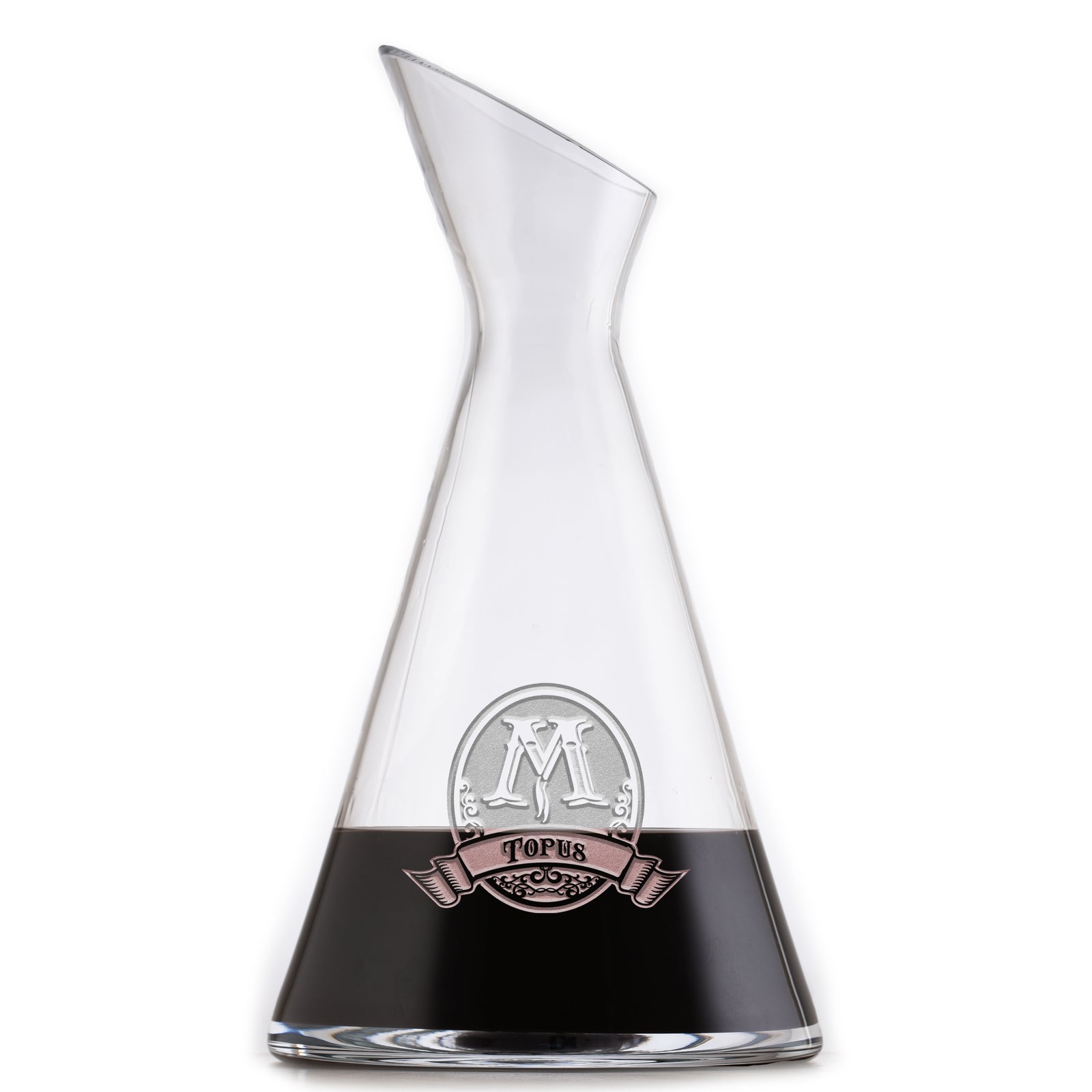 Slant wine carafe deep-carved with a monogram above a last name, filled with a dark drink, on a white background.