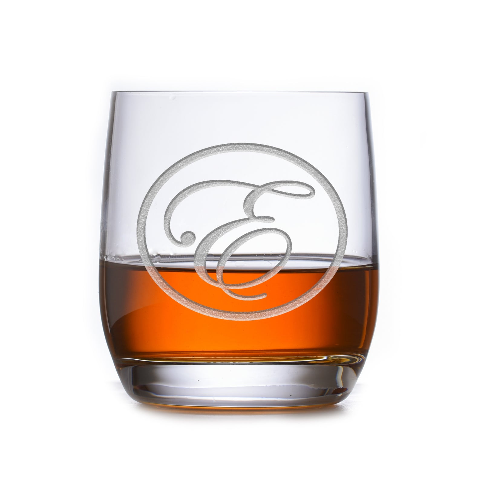 Rocks glass filled with amber liquid, deep-carved with a circular border around a script letter "E," on a white background.