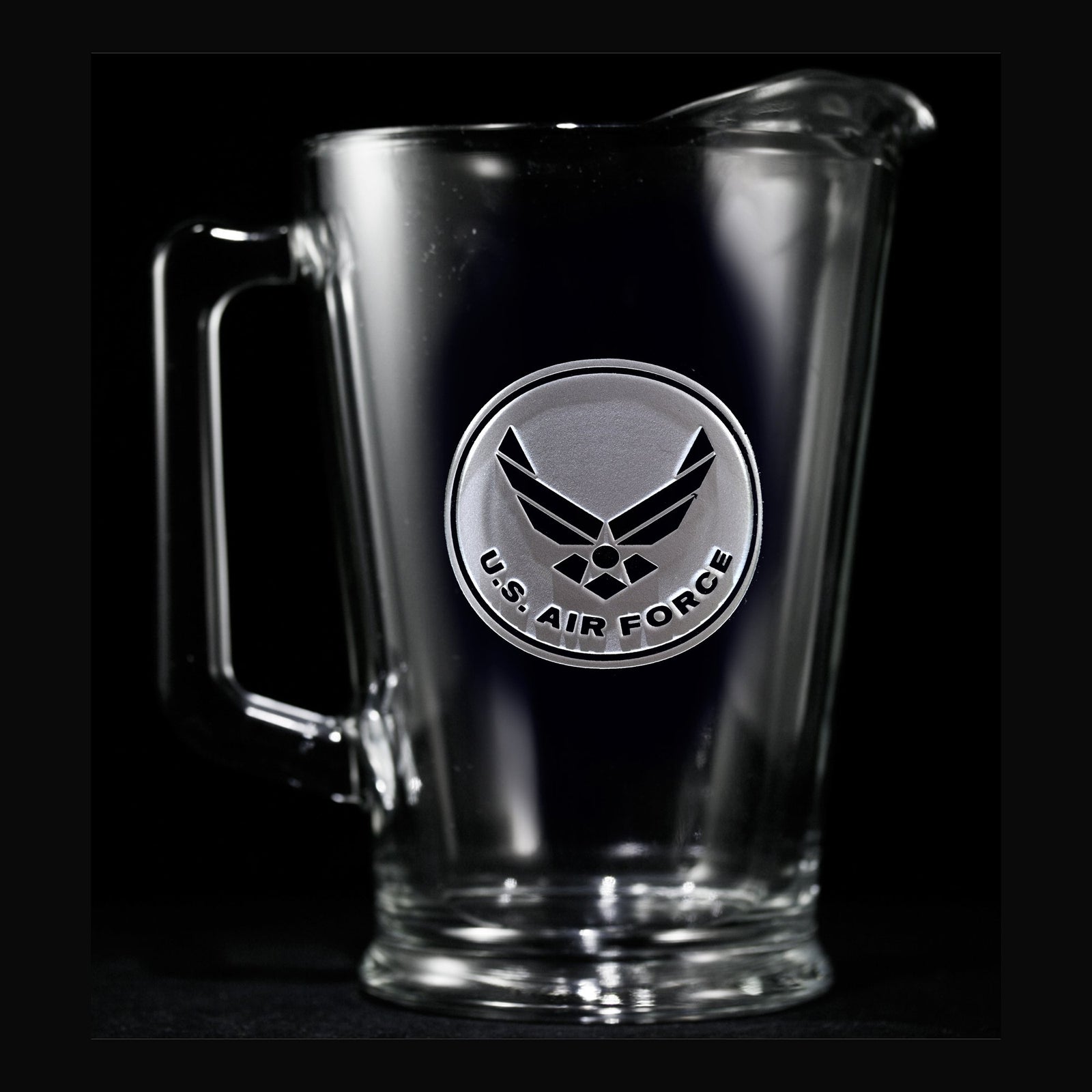 Glass beer pitcher deep-carved with the U.S. Air Force wings emblem in a circular badge, on a black background.
